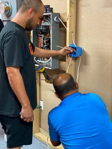 Curso de Electricidad en ITA – Práctica en tableros eléctricos Estudiantes del curso de Electricidad de ITA realizando prácticas de cableado en un tablero eléctrico.