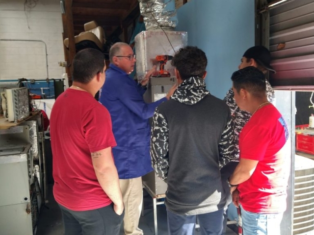 Instructor explicando sistema de aire acondicionado – ITA Instructor explicando sistema de aire acondicionado a estudiantes en taller práctico de ITA.