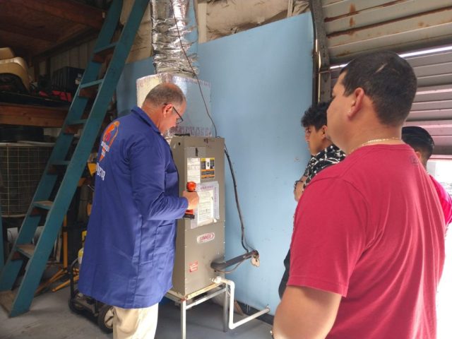 Revisión técnica de equipos HVAC en ITA Grupo de estudiantes revisando equipo HVAC junto a instructor en taller del ITA.