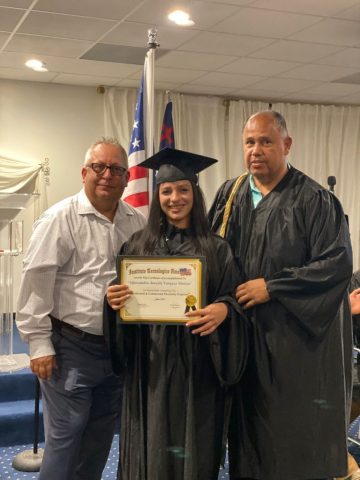 Graduación ITA – Reconocimiento al esfuerzo académico Graduada del Instituto Tecnológico Americano sosteniendo su diploma junto a autoridades del instituto.