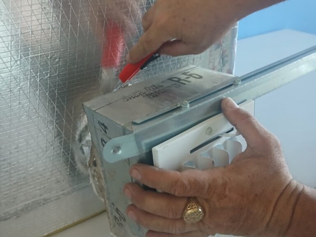 Práctica de instalación de rejillas de ventilación Estudiante del curso de Ductería de ITA realizando la instalación y ajuste de una rejilla de ventilación sobre un ducto metálico aislado, como parte de la formación práctica en sistemas HVAC.